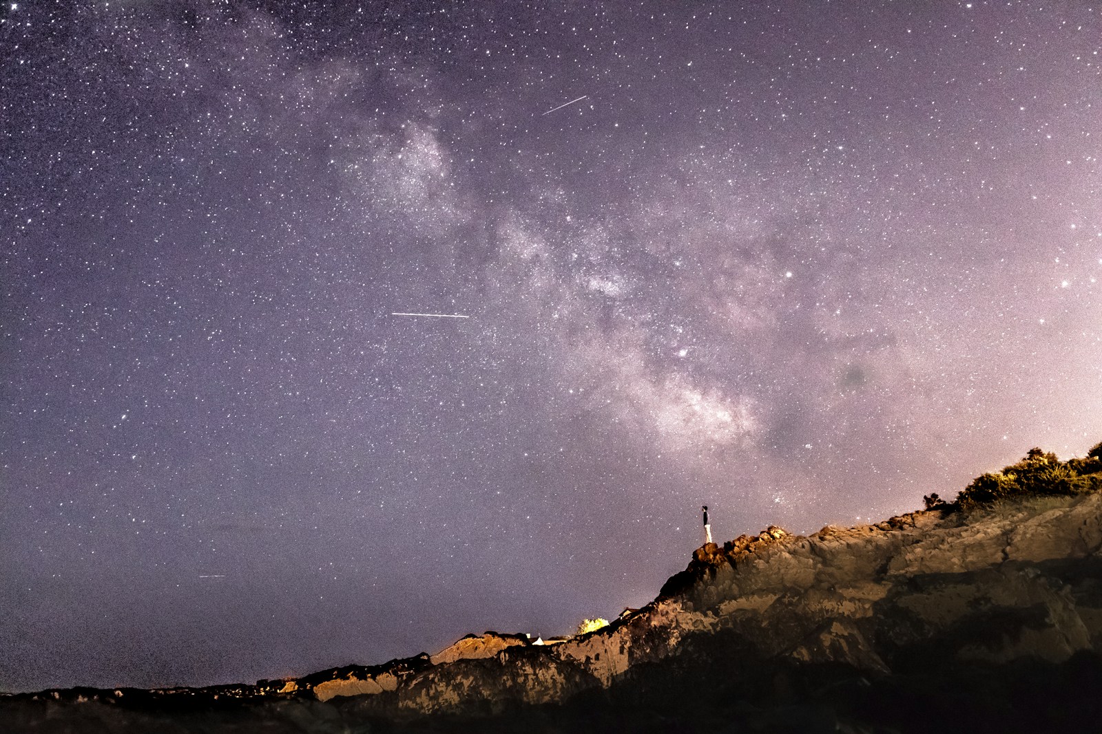person standing on rock formation under starry sky